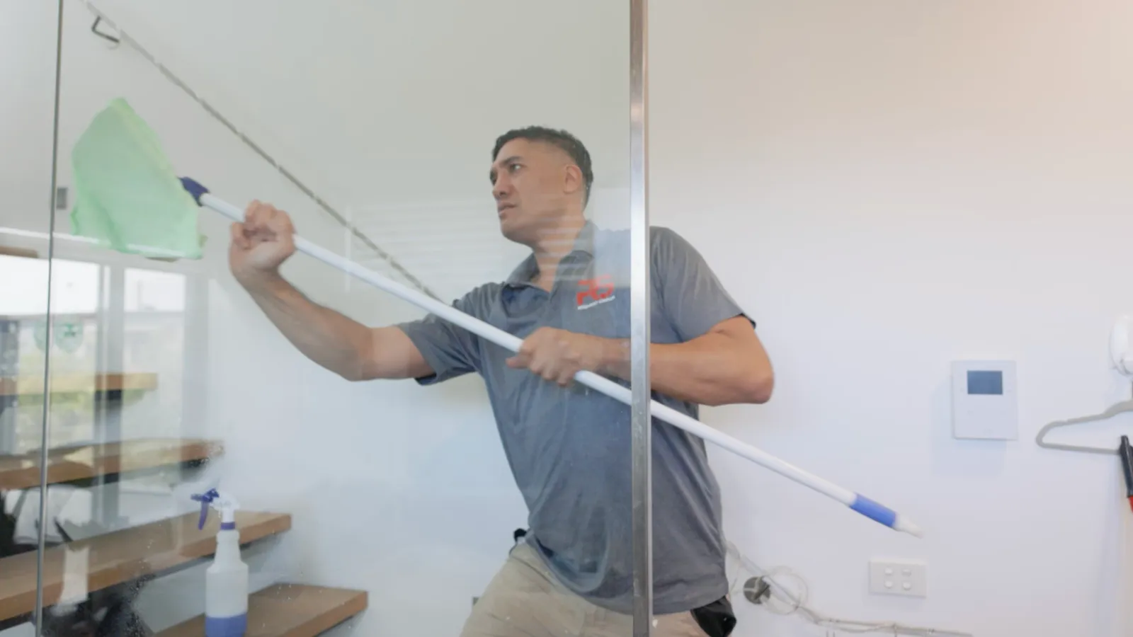 Request Group team member cleaning glass windows in modern property